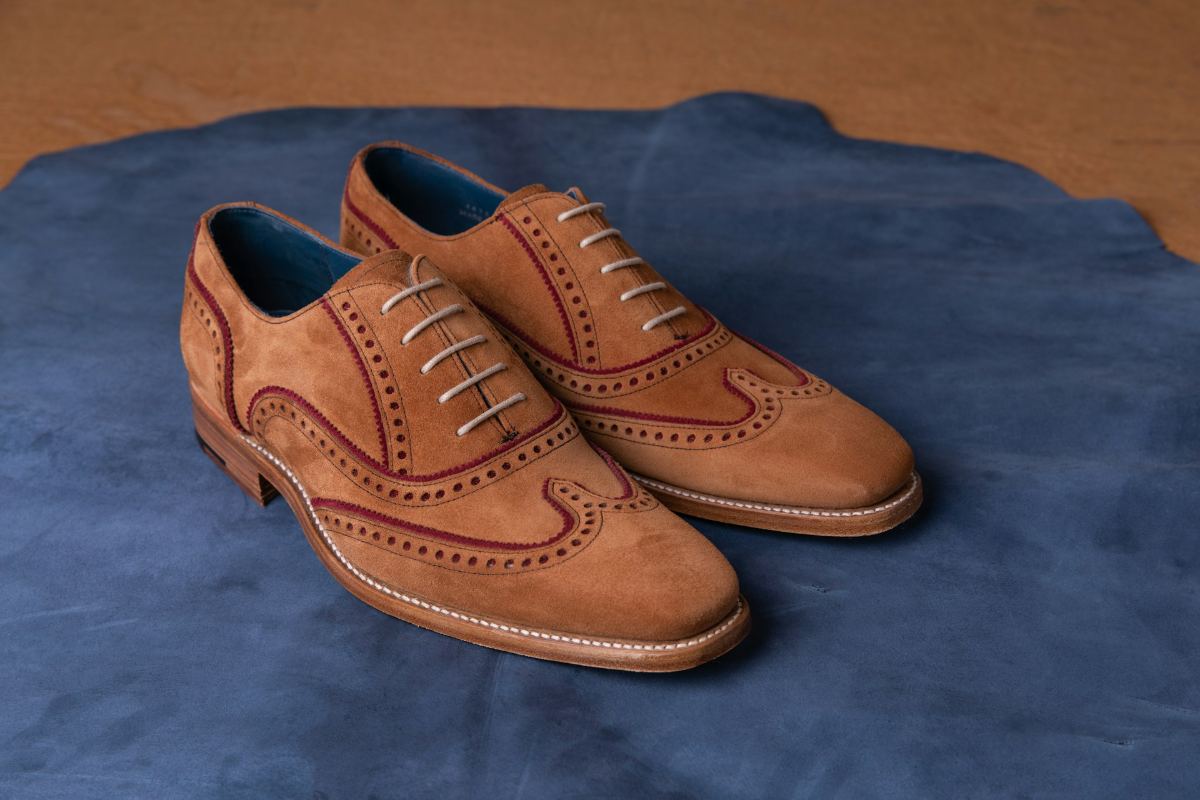 Tan suede brogue shoes on a blue leather hide